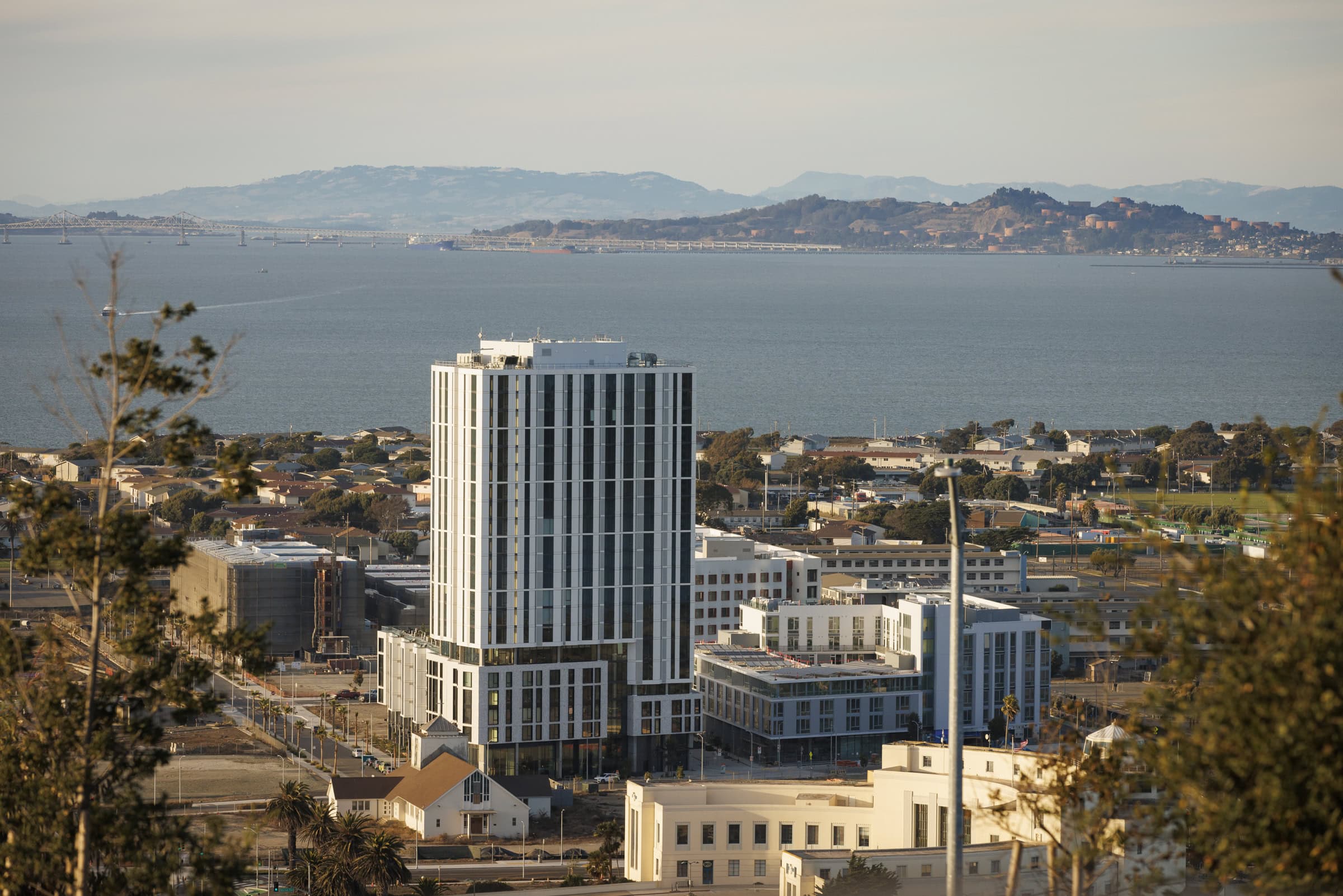 Isle House residential tower on Treasure Island overlooking the San Francisco Bay with the Bay Bridge and East Bay hills in the distance.