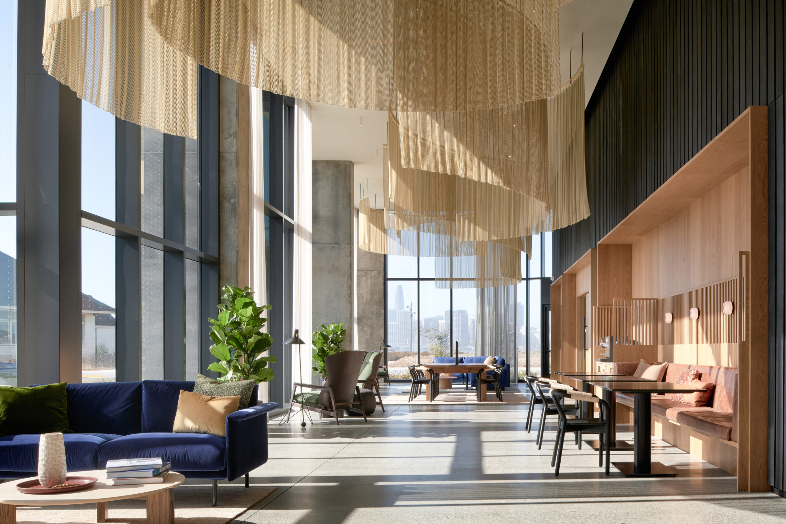 Modern residential lobby at Isle House on Treasure Island with floor-to-ceiling windows and views of the San Francisco skyline.