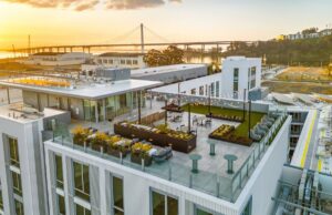 Rooftop terrace with outdoor seating and city views overlooking the San Francisco Bay and Bay Bridge at sunset.